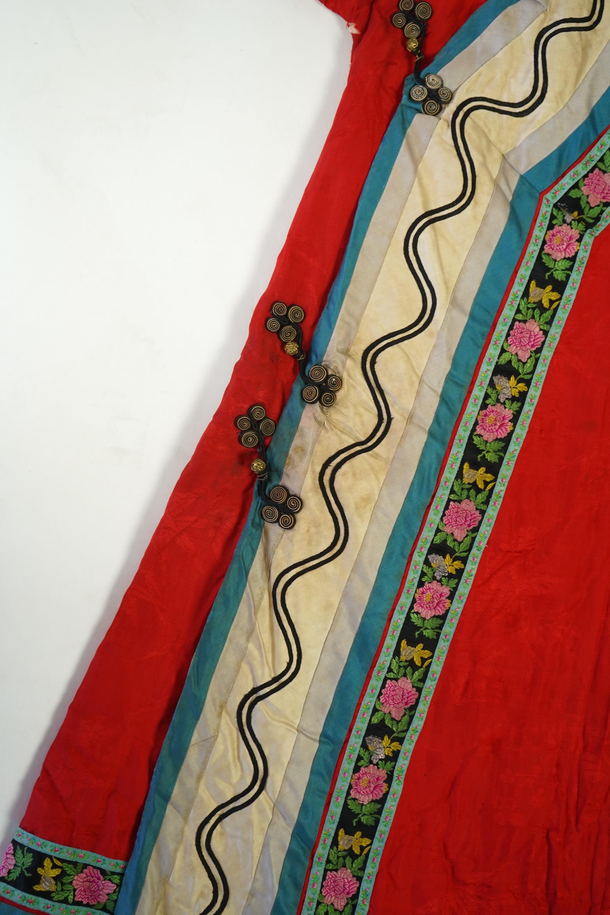 A late 19th century early 20th century Chinese red silk damask quilted Mandarin robe. Decorated with colourful rows braiding and ornate toggling. 116cm long. Condition - minor marks in places, may benefit from specialist